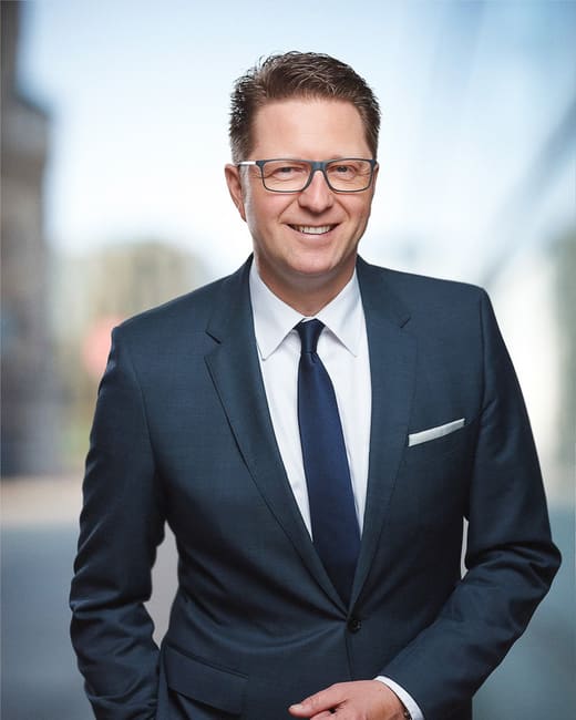 Businessportrait eines Geschäftsführers im Anzug vor einer Bürofassade